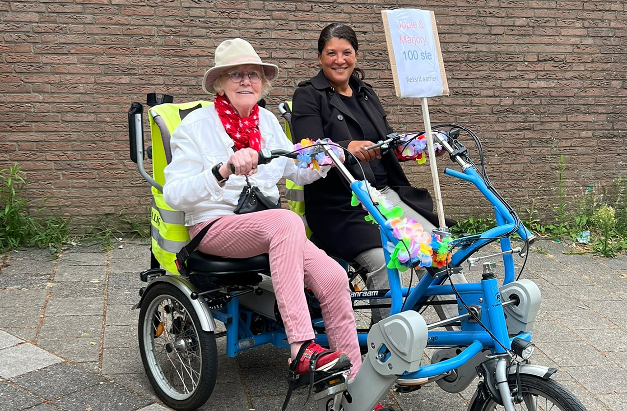 Vrijwilliger en gast fietsen samen de honderdste rit